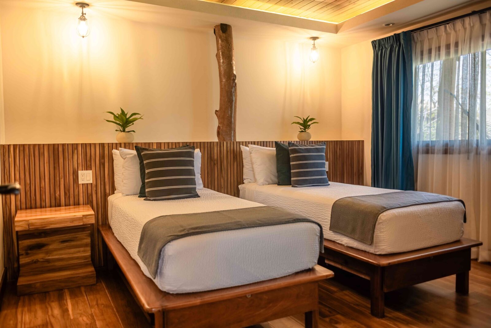 Comfortable room with twin beds, garden views, A/C, and wooden furnishings at TreeCasa Hotel & Resort.